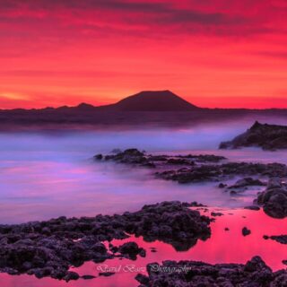 Amanecer hacia Lobos en Fuerteventura con un cielo rojo y vistas a la isla de Lobos