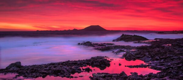 Amanecer hacia Lobos en Fuerteventura con un cielo rojo y vistas a la isla de Lobos